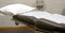 A doctor’s office medical exam table sits ready for use in a clean, well-lit medical room.