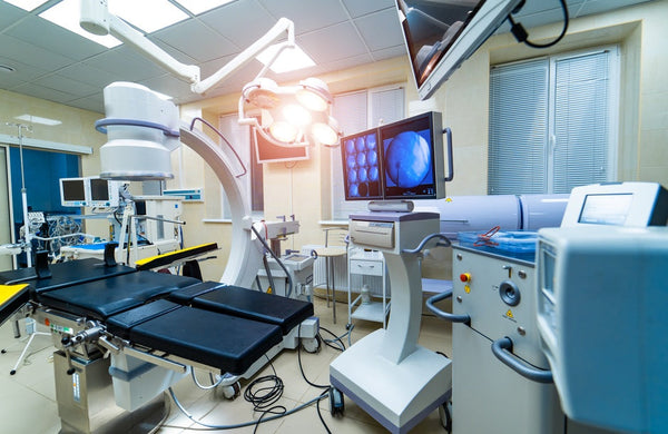  A high-tech operating room is filled with medical equipment like an X-ray scan, surgical table, and EKG machine.