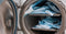 A small autoclave sterilizes medical instruments sealed in blue pouches, which are stacked to capacity.