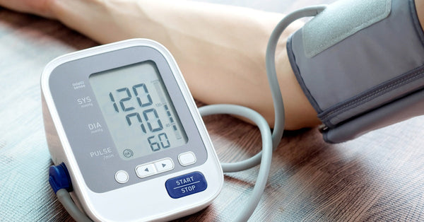 A blood pressure monitor displays a reading of 120/70 with a pulse of 60, with a cuff wrapped around a person's arm.